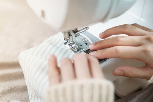 Closeup of woman hand using the sewing machine to sew the face mask during the coronavirus pandemia.