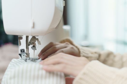 Closeup of woman hand using the sewing machine to sew the face mask during the coronavirus pandemia.