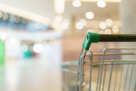 Blurred of supermarket with empty shopping cart.