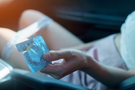 sex in car concept : woman take off her panty in a car and holding condom in hand.