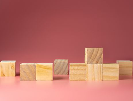 Empty wooden cube on a pink background. For new ideas to be put into the picture.