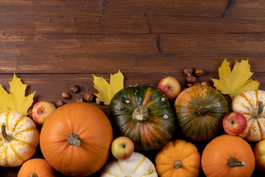 Autumn harvest still life with pumpkins , apples , hazelnuts on wooden background , top view