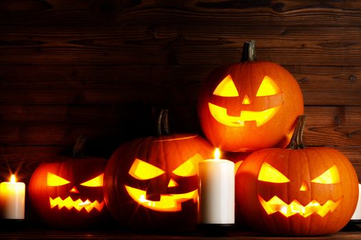 Many Halloween pumpkins head jack o lantern and candles on wooden table background