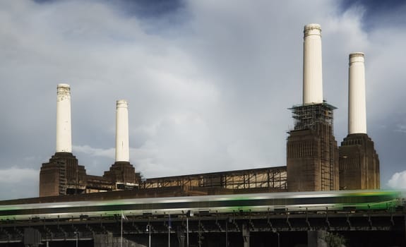 London, United Kingdom - October 01, 2006: Four chimneys of decommissioned coal Battersea power station with green tube train moving fast in foreground.