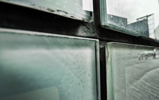 Abstract detail of dirty glass panes on side of the building reflecting the city street. London, United Kingdom