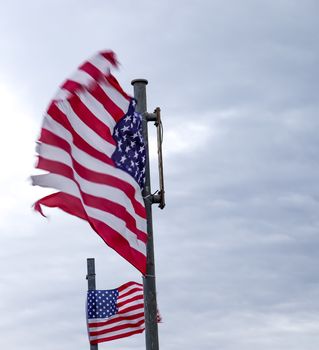 USA flag at a flagpole moving in the wind against the sky