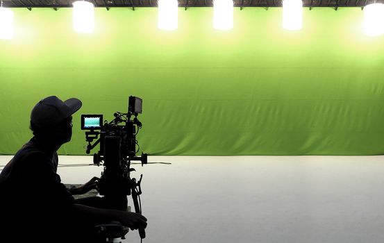 Camera man and tools and white floor and big green screen studio. 