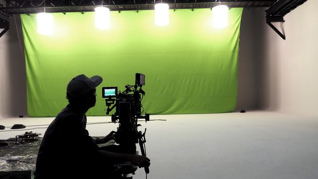 Camera man and tools and white floor and big green screen studio. 