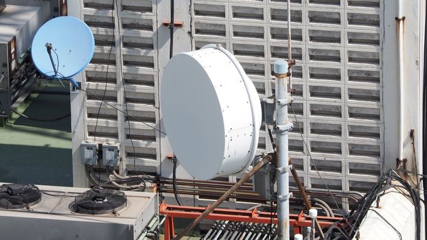 Old big telecommunication satellite dish on roof top of building.