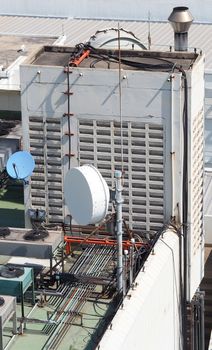 Old big telecommunication satellite dish on roof top of building.