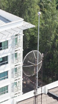 Old big telecommunication satellite dish on roof top of building.