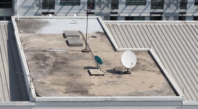 Old big telecommunication satellite dish on roof top of building.