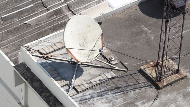 Old big telecommunication satellite dish on roof top of building.