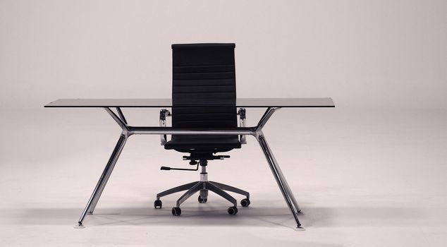 Table with top glass and leather armchair for work and white background.