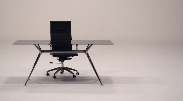 Table with top glass and leather armchair for work and white background.