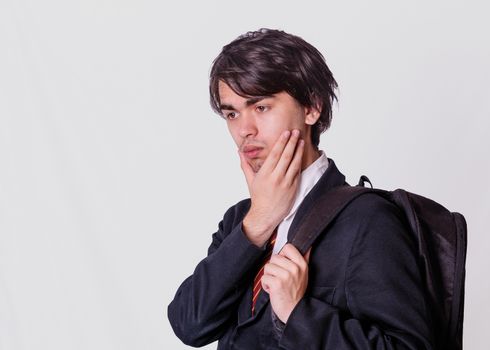 Sad boy in a school suit and with a backpack going back to school