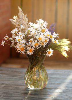 Some wildflowers in a vase on wooden background