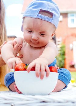 a child grabbing strawberries from a bowl