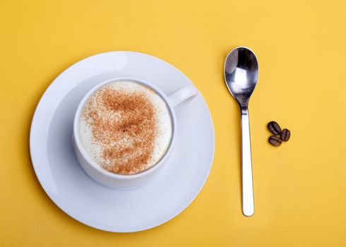 a cup of coffee, spoon, coffee beans, sugar, anis on yellow background