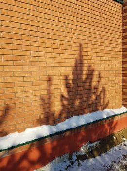 Modern red brick fence with turrets, winter, outdoor, spruce shadow on the wall, Christmas background.