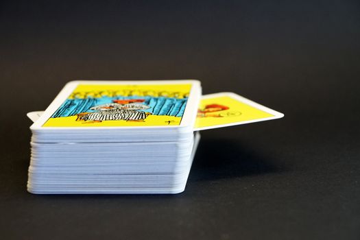 deck of tarot cards with one drawn card close up on black background