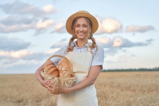 Female farmer standing wheat agricultural field Woman baker holding wicker basket bread eco product Baking small business Caucasian person dressed straw hat apron organic healthy food concept