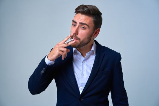 Businessman Business person. Man business suit studio gray background. Modern business person stylish haircut smokes a cigarette Portrait of charming successful young entrepreneur