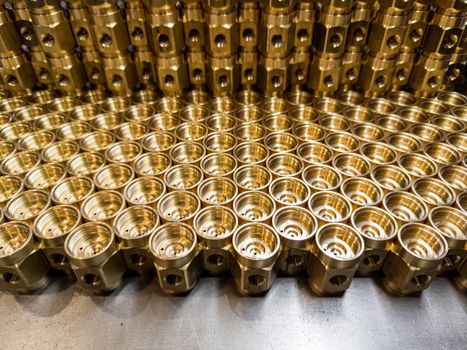 an abstract industrial close-up background of shiny brass metal threaded hexagonal fitting parts.