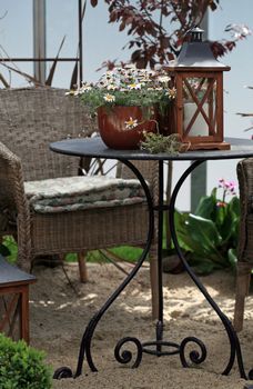 Outdoor table and chair with daisy flower pot and lantern with candle