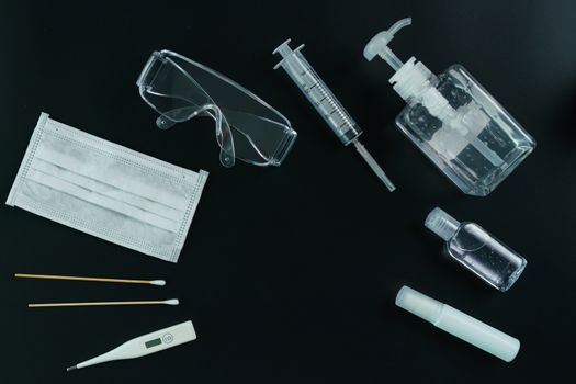 Corona virus medical equipment: Medical masks, safety glasses, syringe, cotton swab, sanitizer and thermometer with petri dish on the table. Coronavirus, Covid-19 protection.