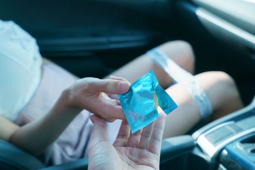 sex in car concept : woman take off her panty in a car and holding condom in hand.