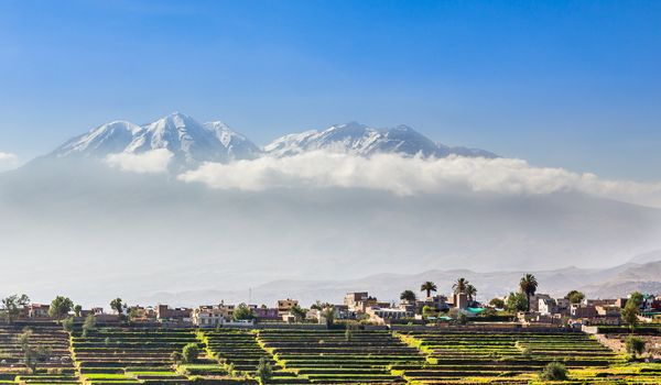 Snow capes of chachani Volcano over the fields and houses of peruvian city of Arequipa, Peru