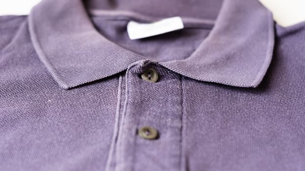Detail of the collar and buttons of a purple polo shirt. Sportswear and fashion