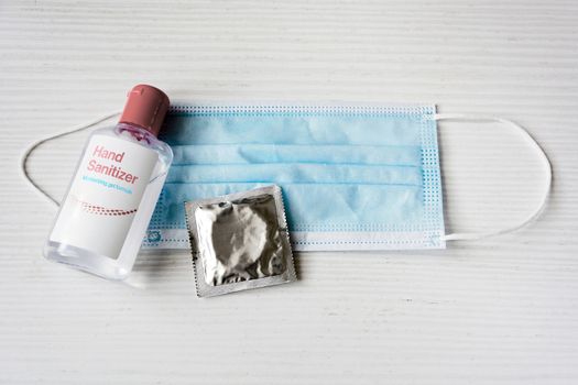 a bottle of hand sanitizing gel, a condom and a surgical mask on a white background. Safety and well-being. Sexual disease and virus prevention tools