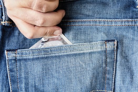 the hand of a man who takes a condom in the back pocket of his jeans. Prevention of sexually transmitted diseases. Safe sex