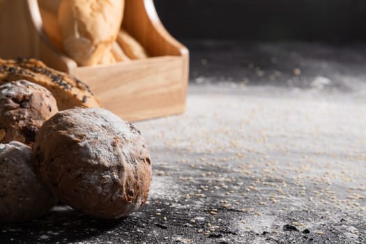 Close-up loaves of bread on the wooden black table with sesame.