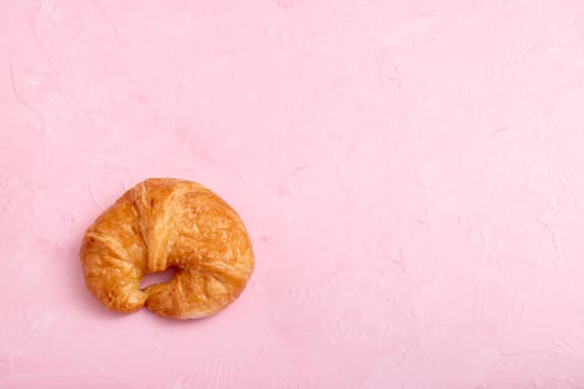 Top view a croissant on the pink background and texture.
