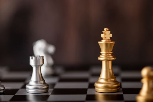 Gold king in game on the chessboard with wooden background