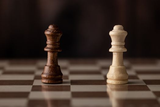 Queens on the chessboard and wooden background