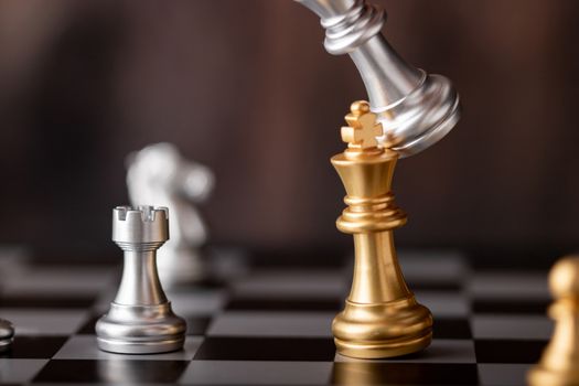 hand holding silver king attack gold leader in game on the chessboard