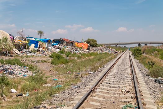 Houses made with plastic and cardboard waste on one side of the train track. Extreme poverty