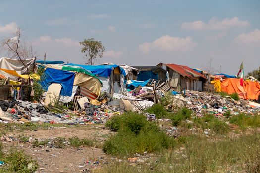 Houses made with plastic and cardboard waste on one side of the train track. Extreme poverty