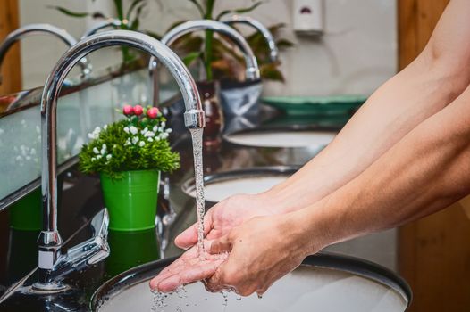 Closeup hands washing with Chrome faucet and water for Coronavirus pandemic prevention in bathroom, self responsibility cleaning, hand hygiene corona virus protection concept