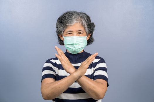 Portrait of asian old woman wearing face surgical mask and say no action to coronavirus  infection on blue color background, covid19 outbreak and pandemic, protection against virus concept