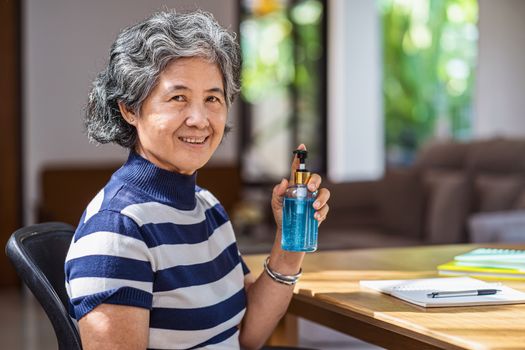 Portrait of Asian old man woman showing hand sanitizer by pumping alcohol gel and washing before working in work from home period,coronavirus or covid19 outbreak,social distancing and responsibility