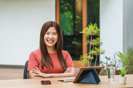 Portrait of Asian business woman using technology tablet for working from home in outdoor home and garden, startups and business owner, covid19 social distance and responsibility or quarantine concept