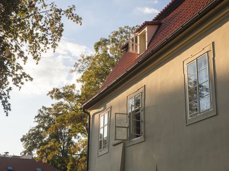old prague baroque house at Kampa with open window in golden hour light, trees and sky background.