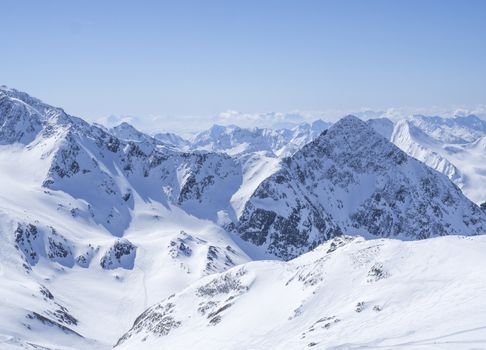 View on winter landscape from the top of Schaufelspitze mountain at Stubai Gletscher ski area with snow covered peaks at spring sunny day. Blue sky background. Stubaital, Tyrol, Austrian Alps.