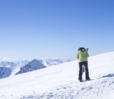 Skier at the top of Schaufelspitze mountain at Stubai Gletscher ski resort preparing to go down into the valley. Snow covered peaks. South Tyrol, Austrian Alps. Nature and sport background, blue sky sunny spring day.
