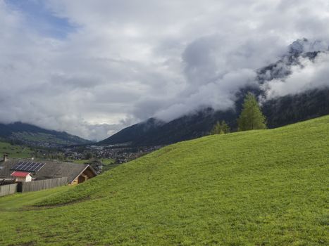 Lush green meadow,Idyllic spring mountain rural landscape. View over Stubaital or Stubai Valley near Innsbruck, Austria with village Neder, white clouds and fog